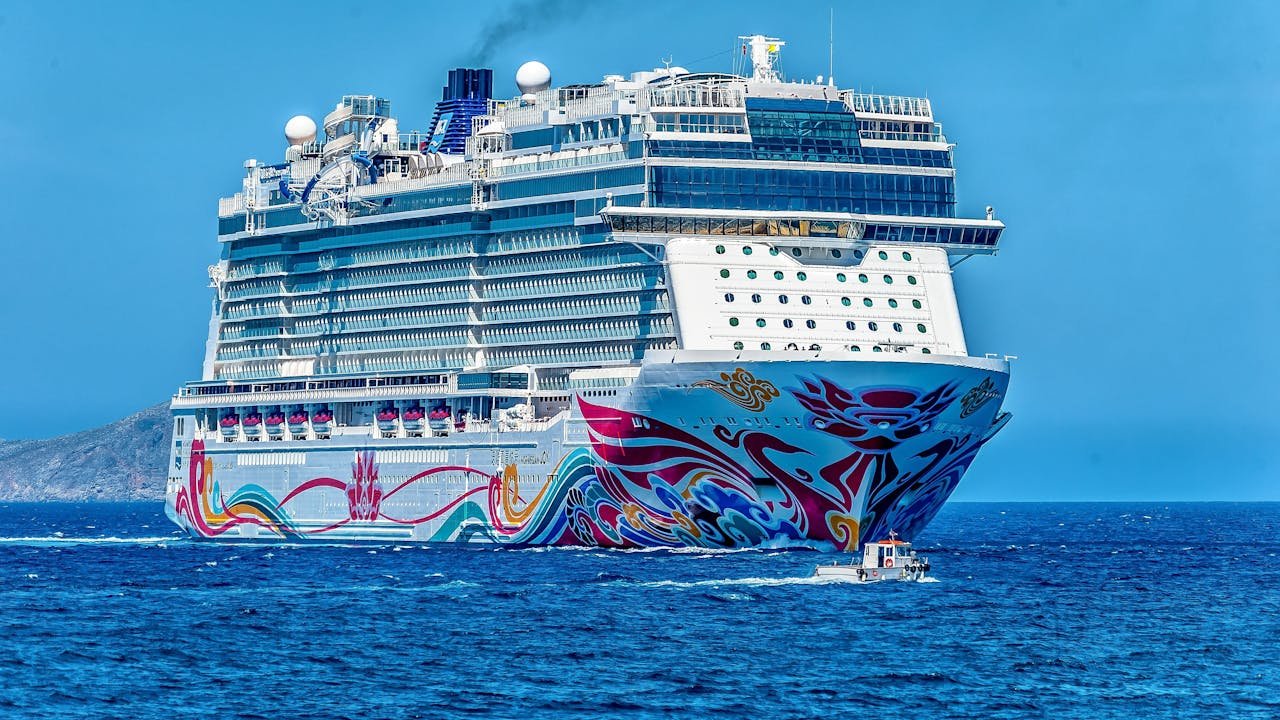 portfolio-01 A colorful cruise ship sailing on the open sea under a clear blue sky. Ideal for tourism and travel themes.